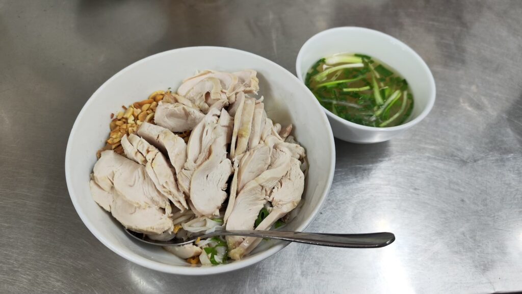 A bowl of dry pho and another bowl of the soup.