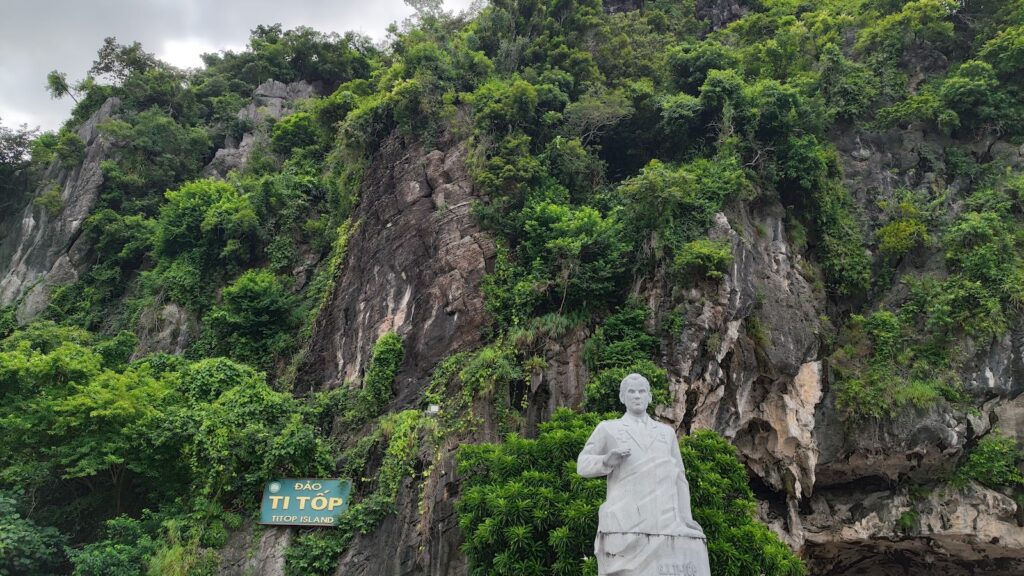 Statue of Mr. Ti Top, in front of a cliff.